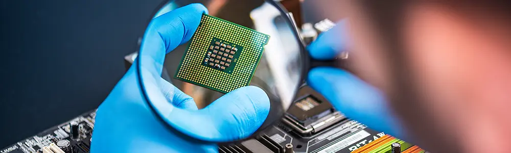 person holding magnifying glass up to processor chip