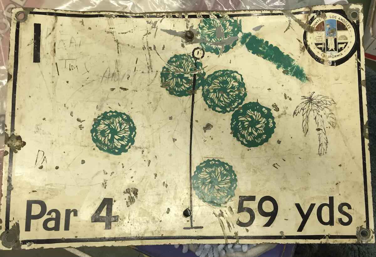 a beat-up metal sign for a disc golf hole in yards