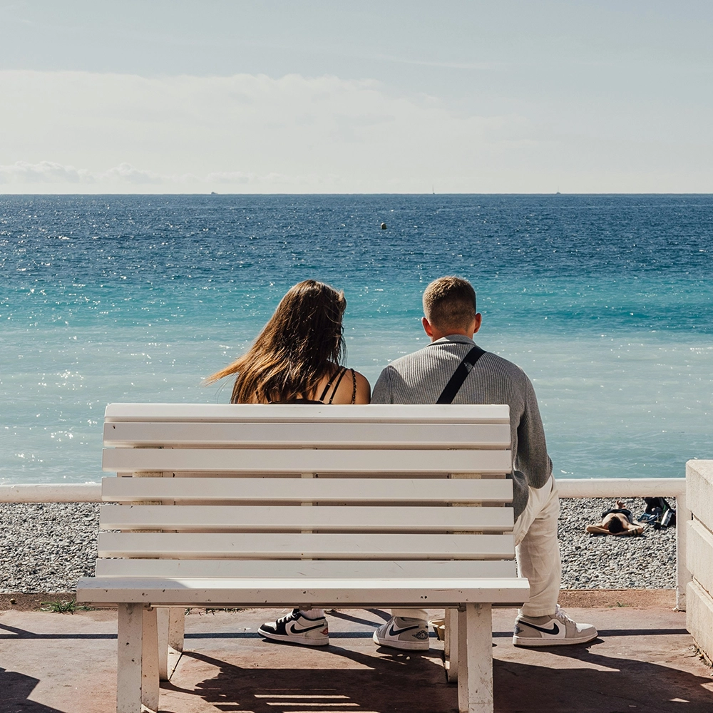 A couple sits relaxing and overlooking the ocean.