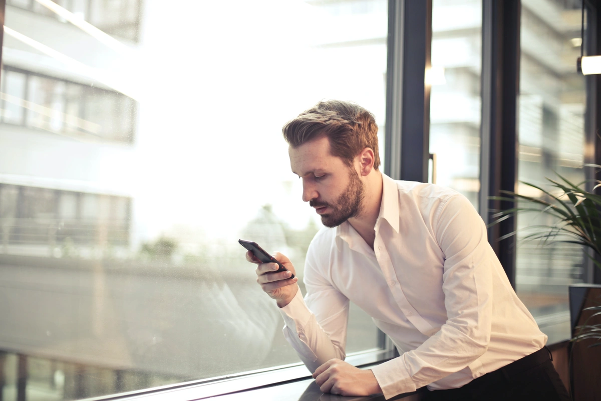 A man in a white dress shirt leans against a big office window and makes an outbound call.  Facebook: Call tracking software can work seamlessly with existing Customer Relationship Management (CRM) systems. Learn more here
