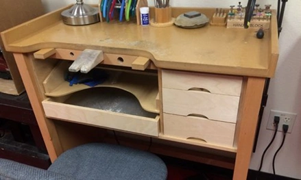 Image of a traditional jewelers bench with three drawers and some tools on top