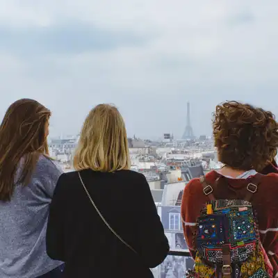 Three young women overlook Paris with Eiffel Tower.