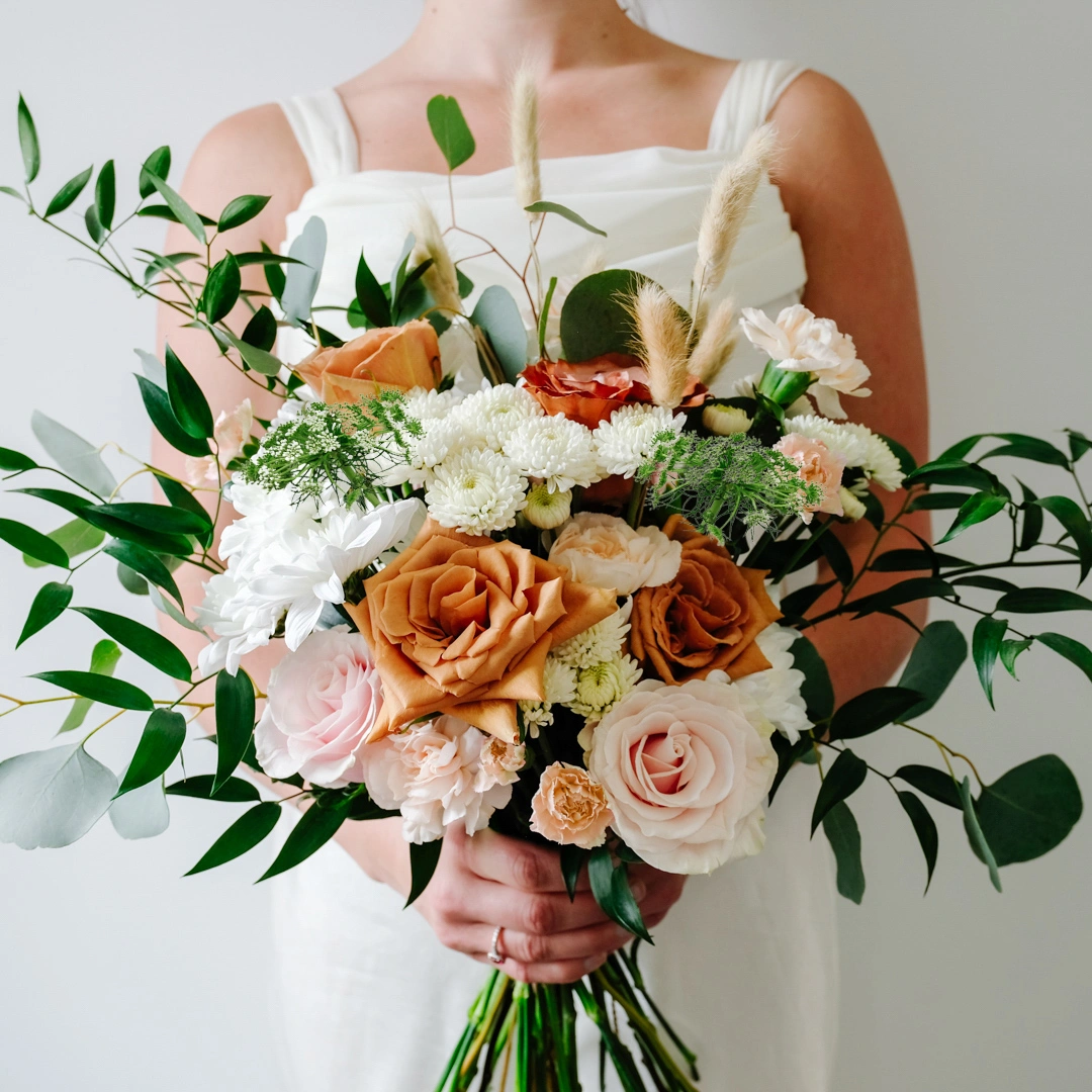 Pastel fall bridal bouquet with large terracotta roses, blush pink roses and eucalyptus greenery.