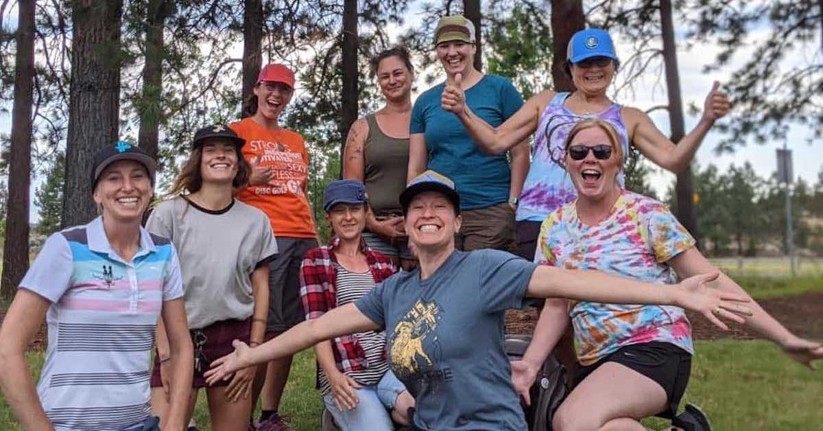 A group of happy and excited female disc golfers pose for the camera