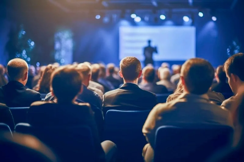 Large event audience seated in a venue watching a live presentation on stage