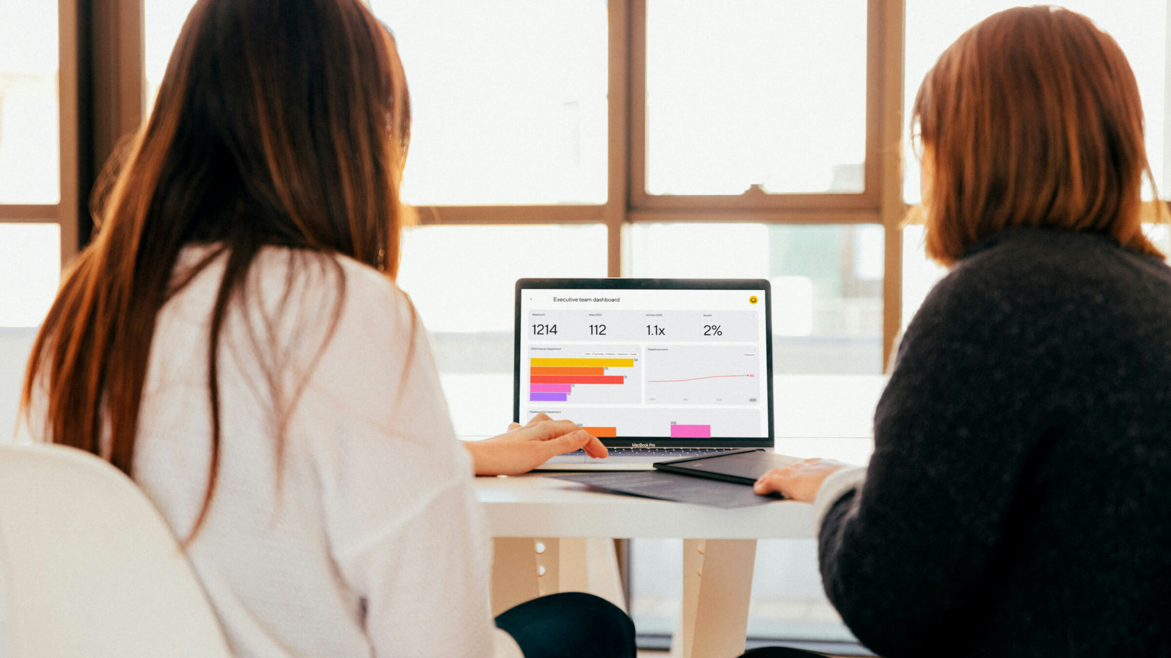 Two people sitting together at a table reviewing a Dandi dashboard on a laptop computer screen.