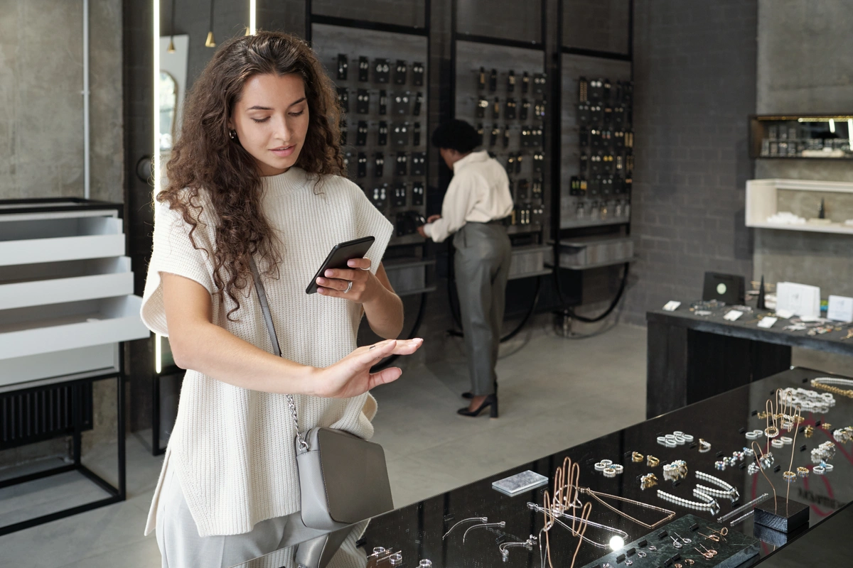 woman in jewelry store taking photo of ring on her hand with a phone