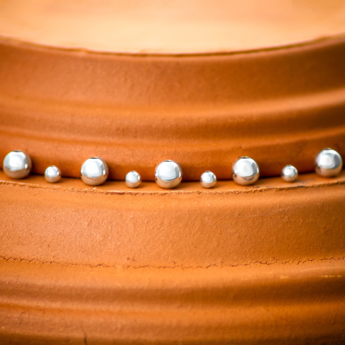 Sterling Silver beads that have been slightly desaturated on terra-cotta pot