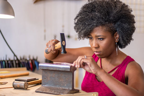 Woman hammering in jewelry studio