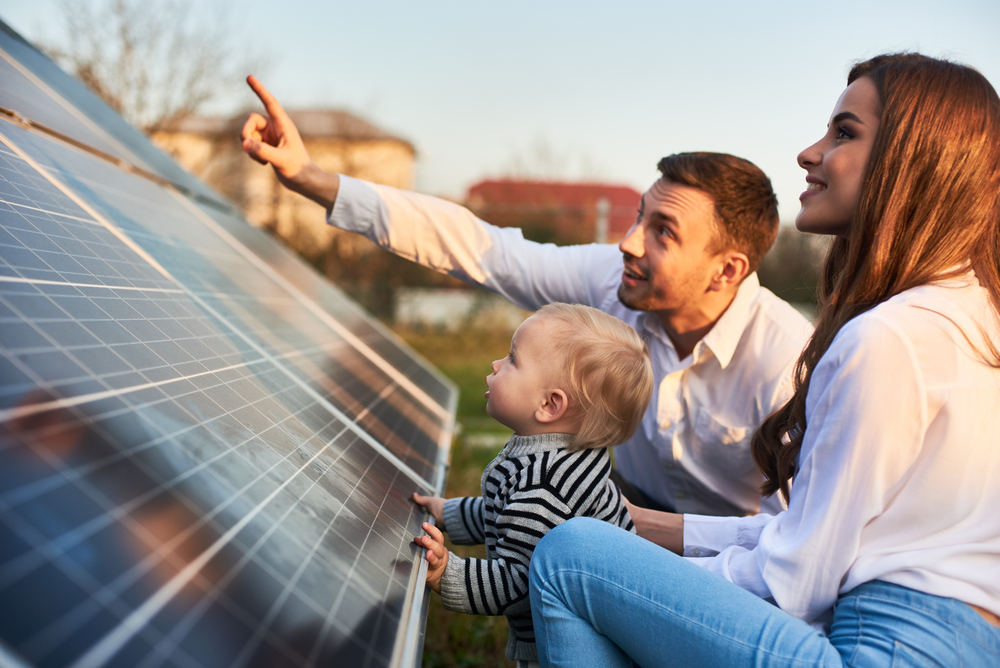 Young family looking at solar panels at sunset