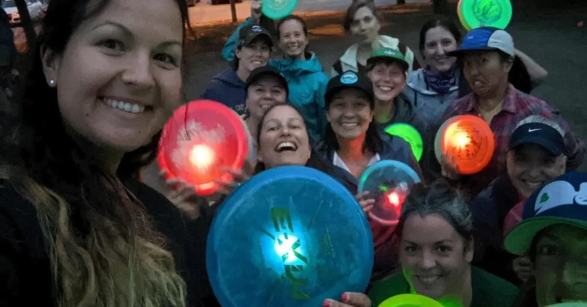 A group of people pose for a photo with with discs that glow or have lights taped to them