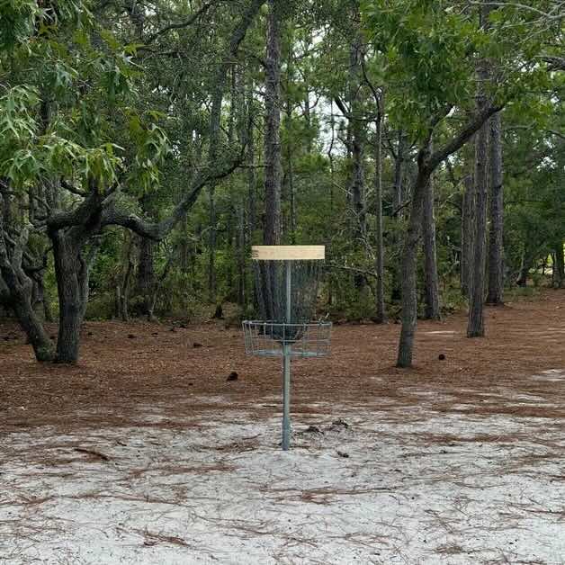 A disc golf basket in sandy, coastal soil