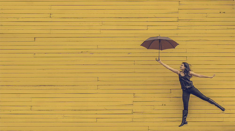 Woman with umbrella on yellow background