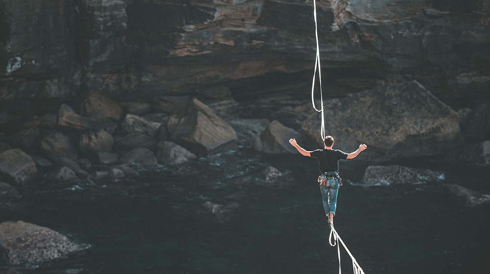 Man slacklining over mountain river