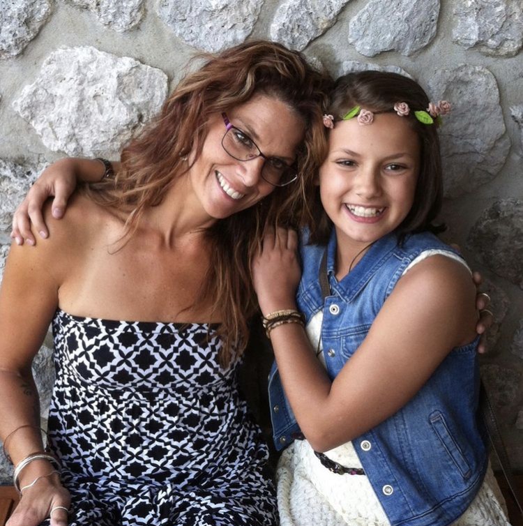 woman and her young daughter with their arms around each other smiling