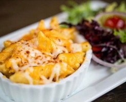 Cheesy dish in a bowl with green salad beside.