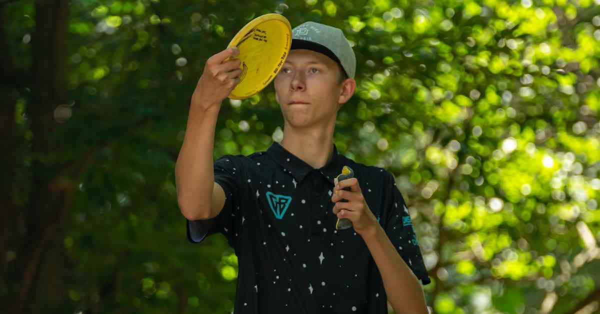 A yound man concentrates lining up a disc golf throw with a yellow disc