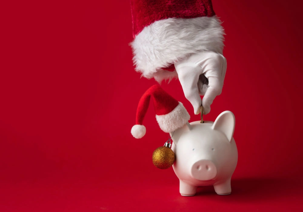 Santa puts a coin in a piggy bank to start saving during the holidays.