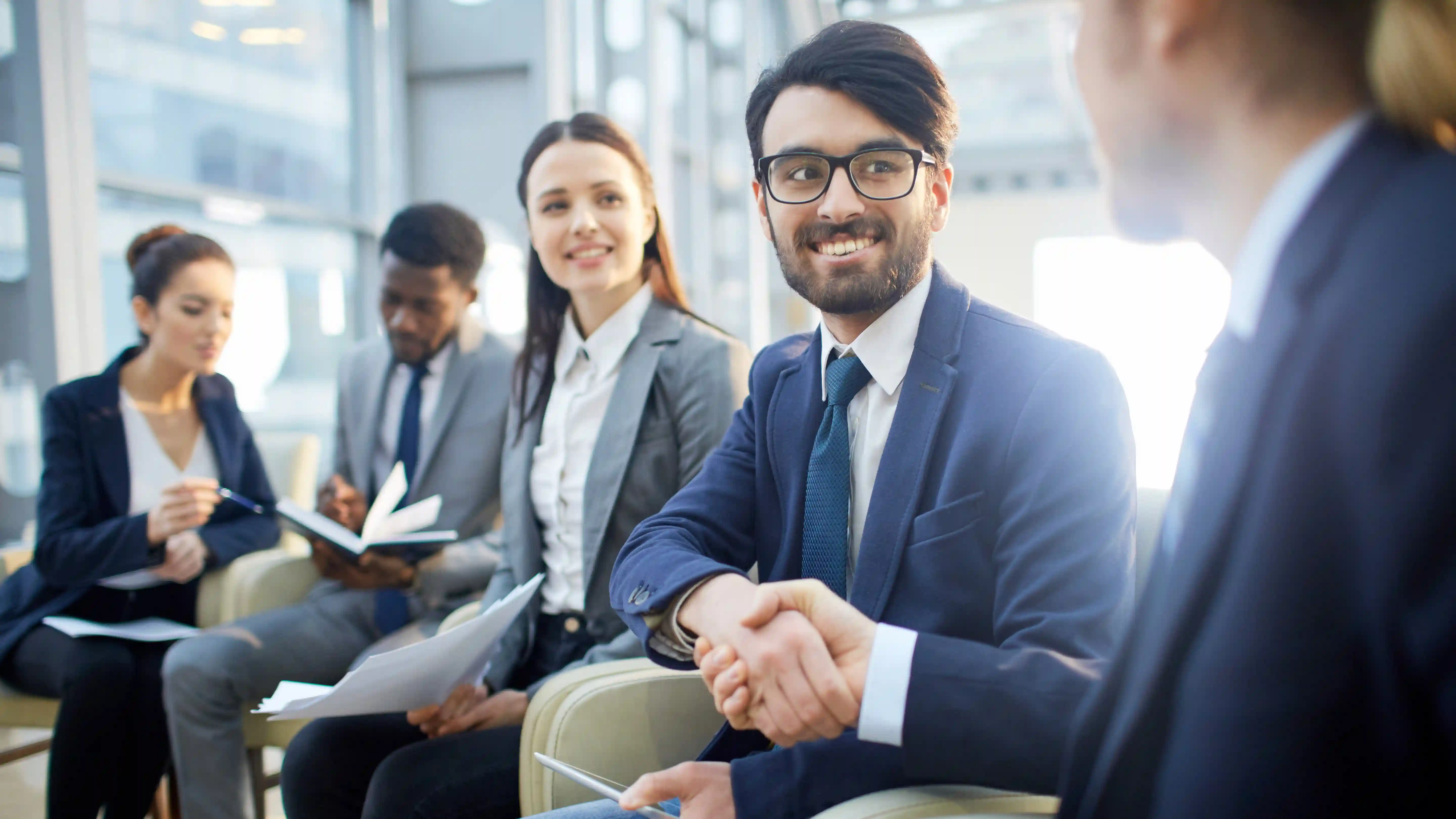 Diverse business professionals handshaking at meeting representing ethical partnership through impact-led hiring