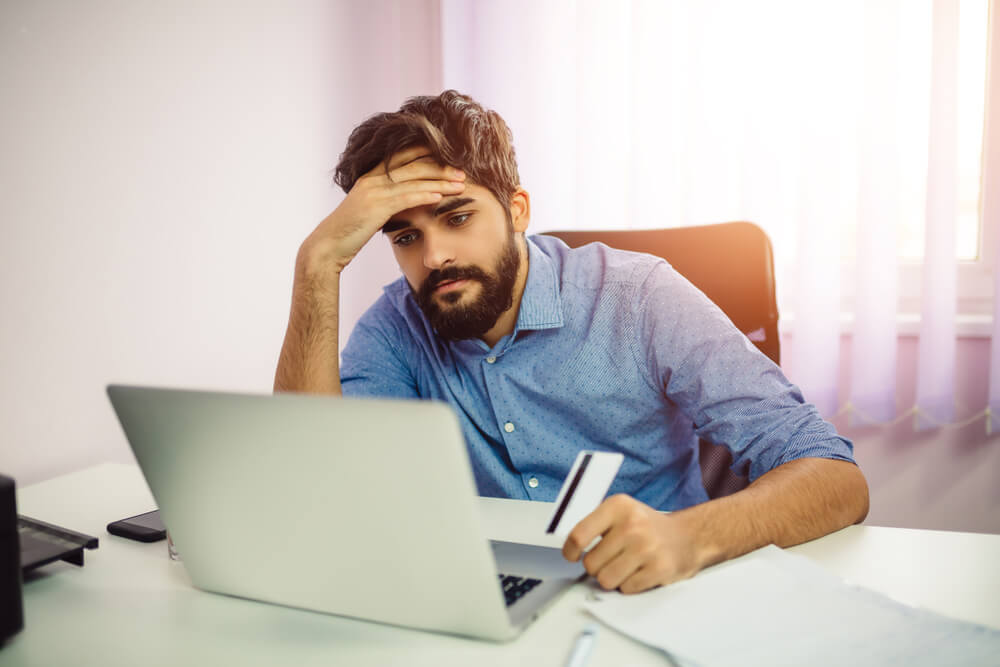 Man looking at his laptop to find out how a missed credit card payment will impact his credit score