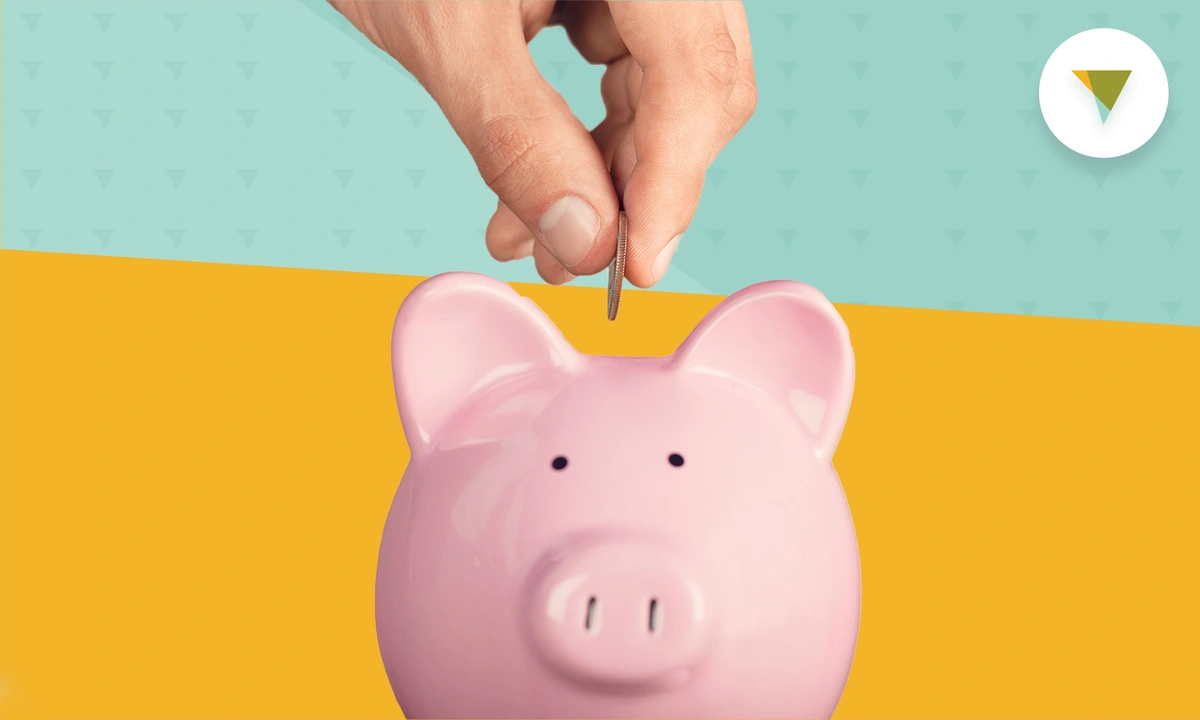 Hand putting coin into piggy bank.