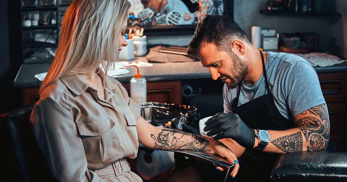 tattoo artist working on client in studio