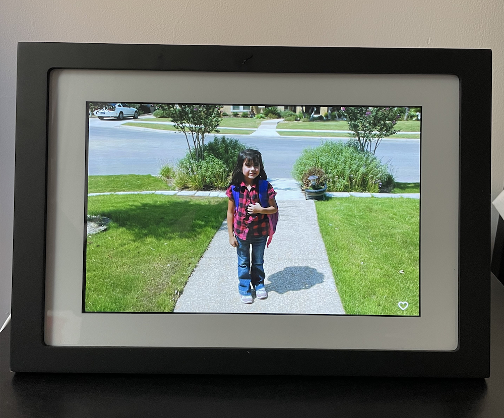 Child with backpack posing for first day of school on digital photo frame