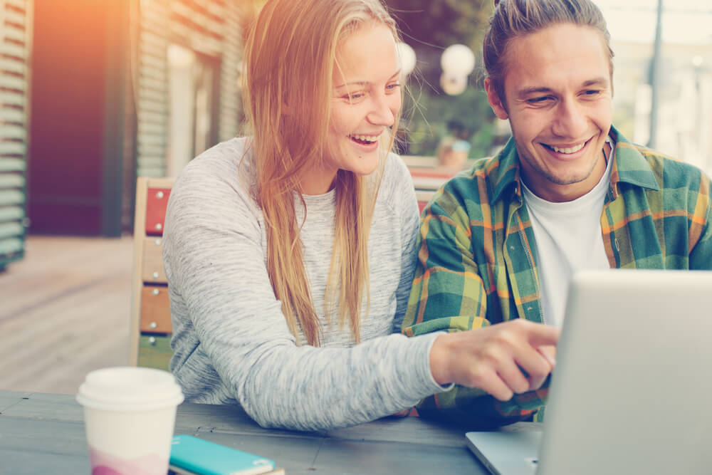Happy couple looking and pointing at laptop screen