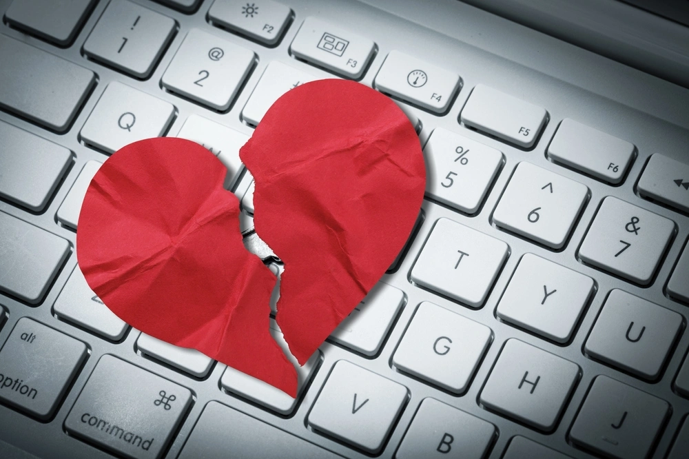 Red paper heart torn on top of a computer keyboard