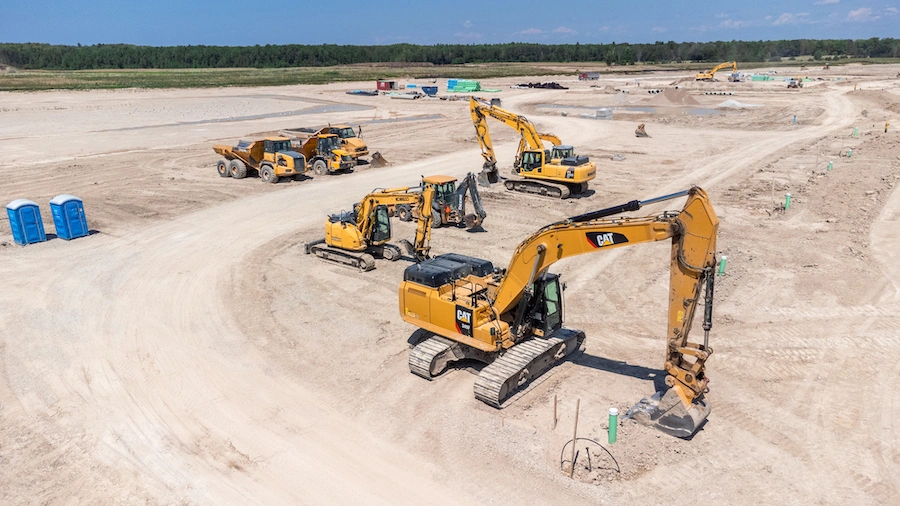 A yard of caterpillar equipment including 3 different sized excavators, a backhoe, and three articulating dump trucks
