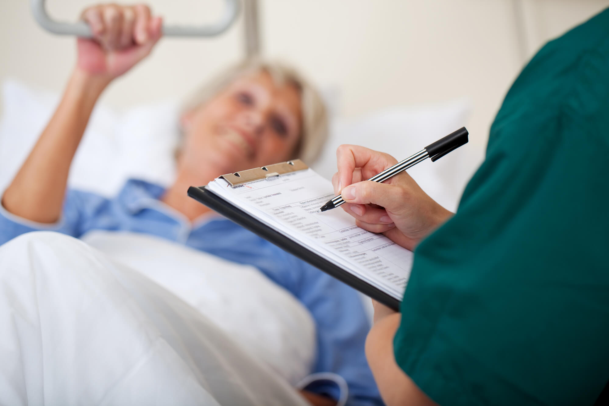 Doctor Writing On Clipboard for a Diagnosis While Looking At A Patient