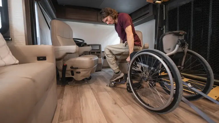 Person getting out of wheelchair inside Class A RV
