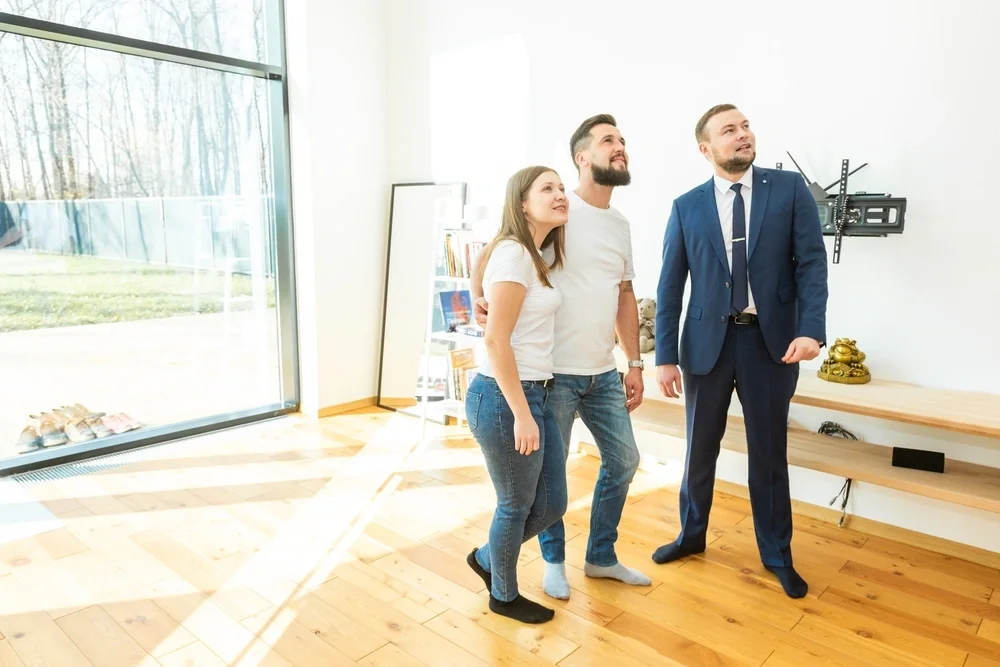 A young couple being shown around a house by a salesman.