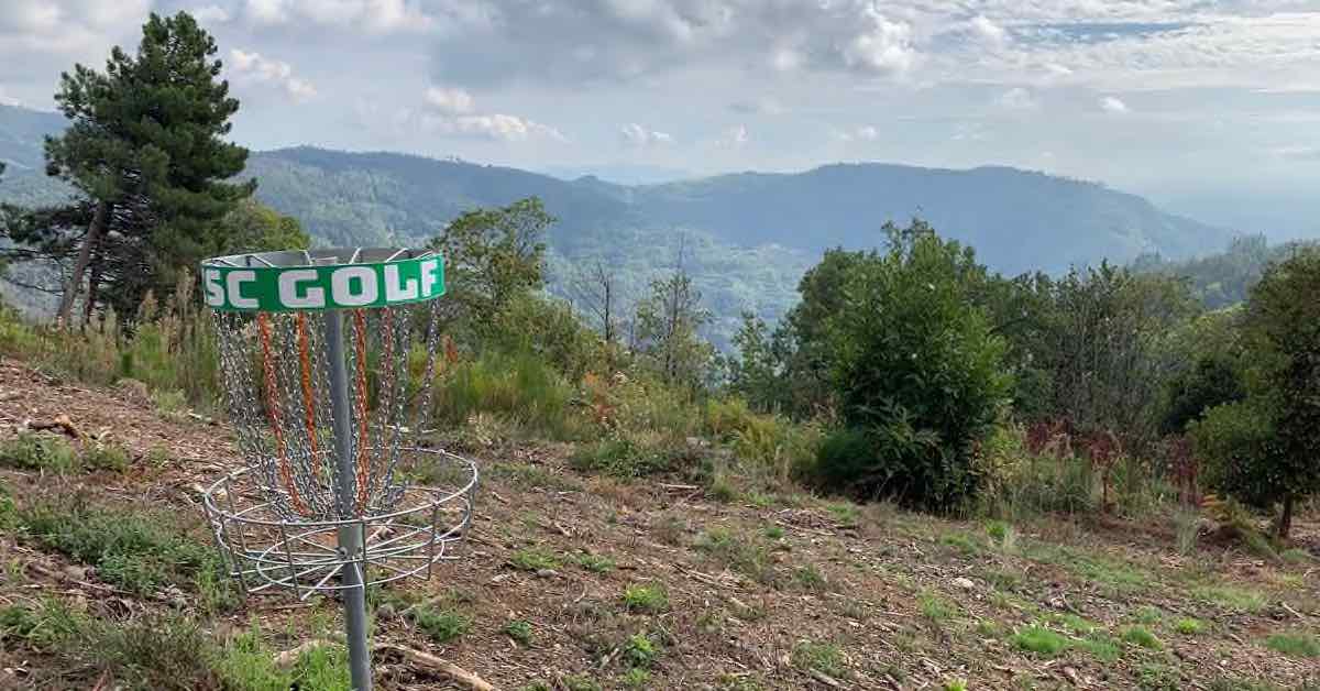 A disc golf basket with a view of green mountains behind