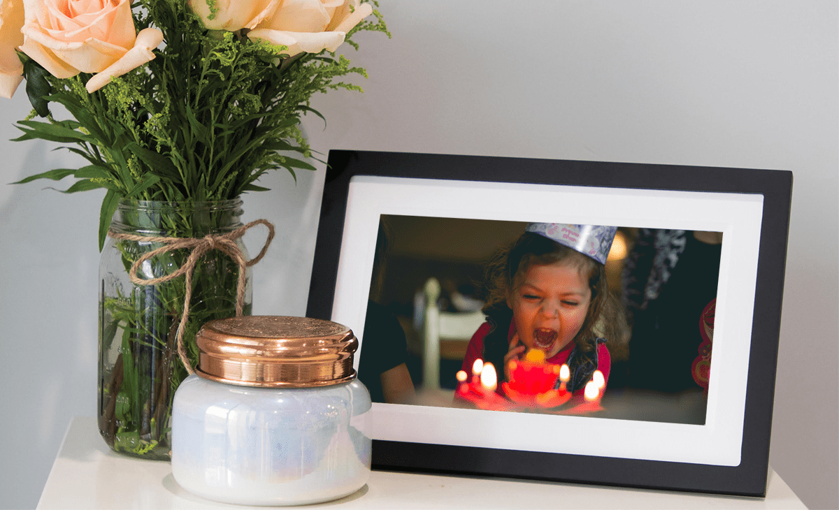 Girl blowing out birthday cake candles on digital photo frame