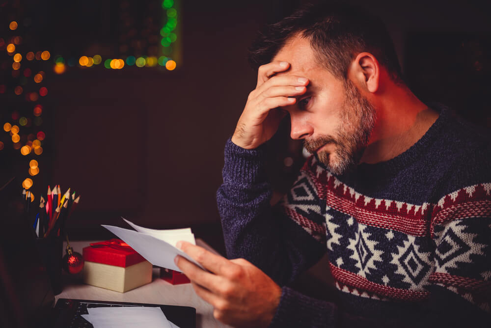 man stressed over holiday debt