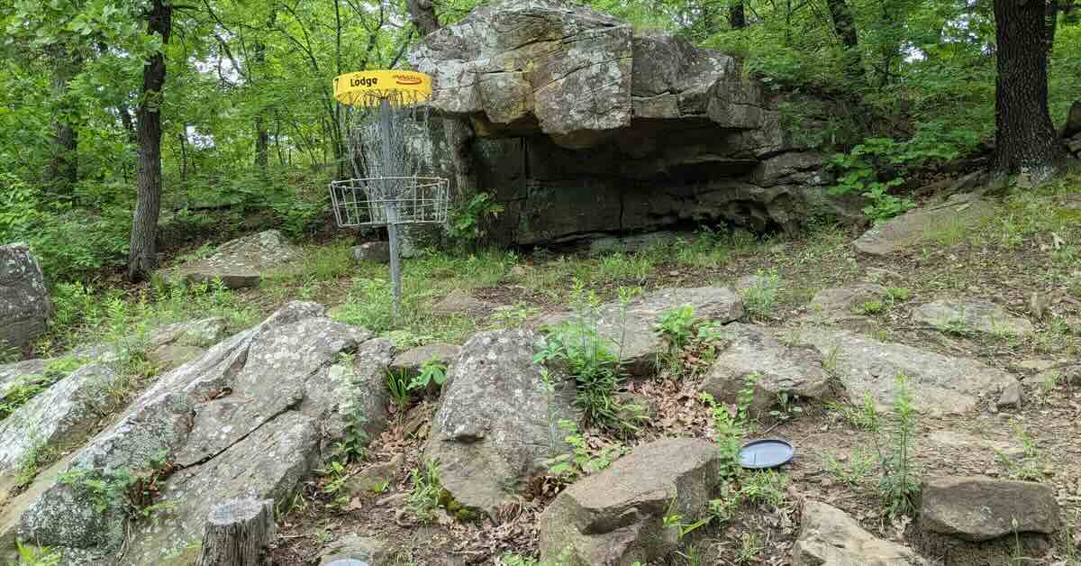 A disc golf basket near a rocky outcrop