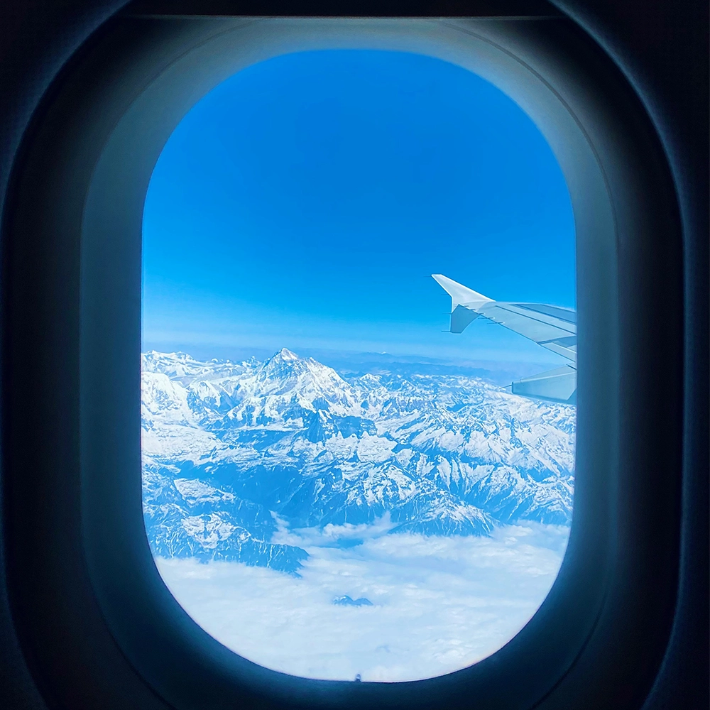 Plane window view of high altitude mountains.