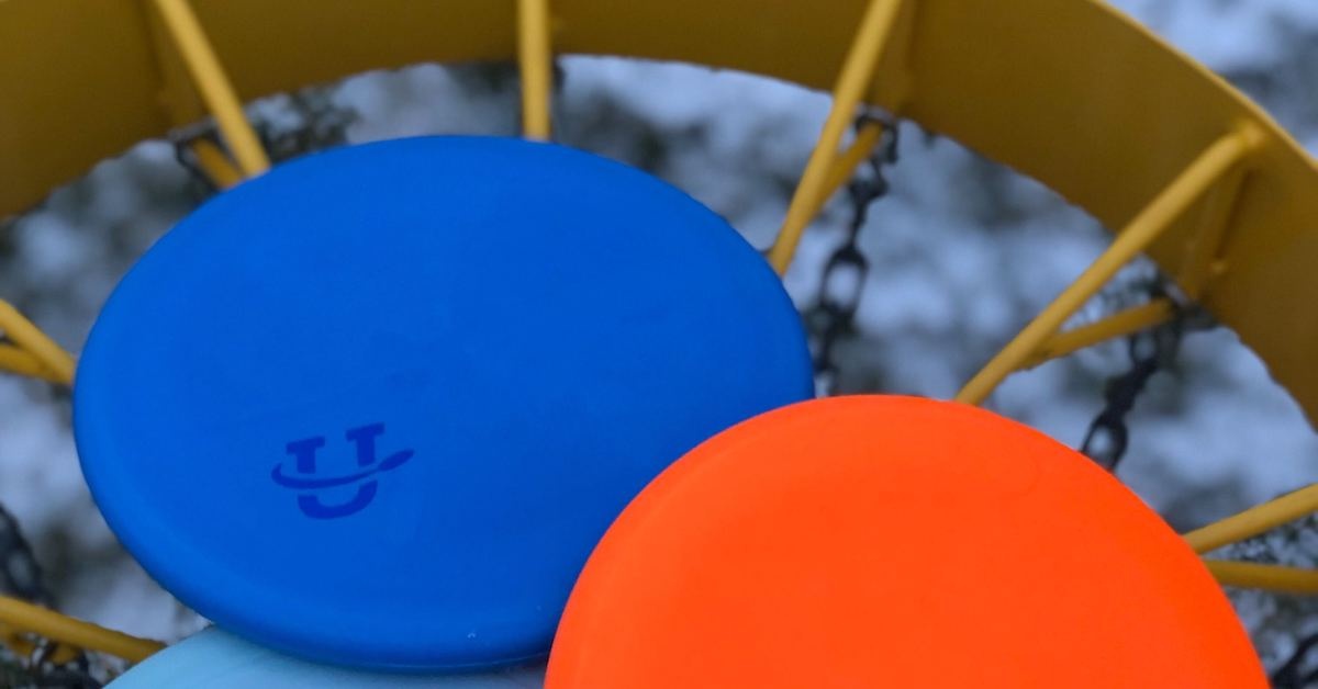 Two disc golf putters on top of a disc golf basket