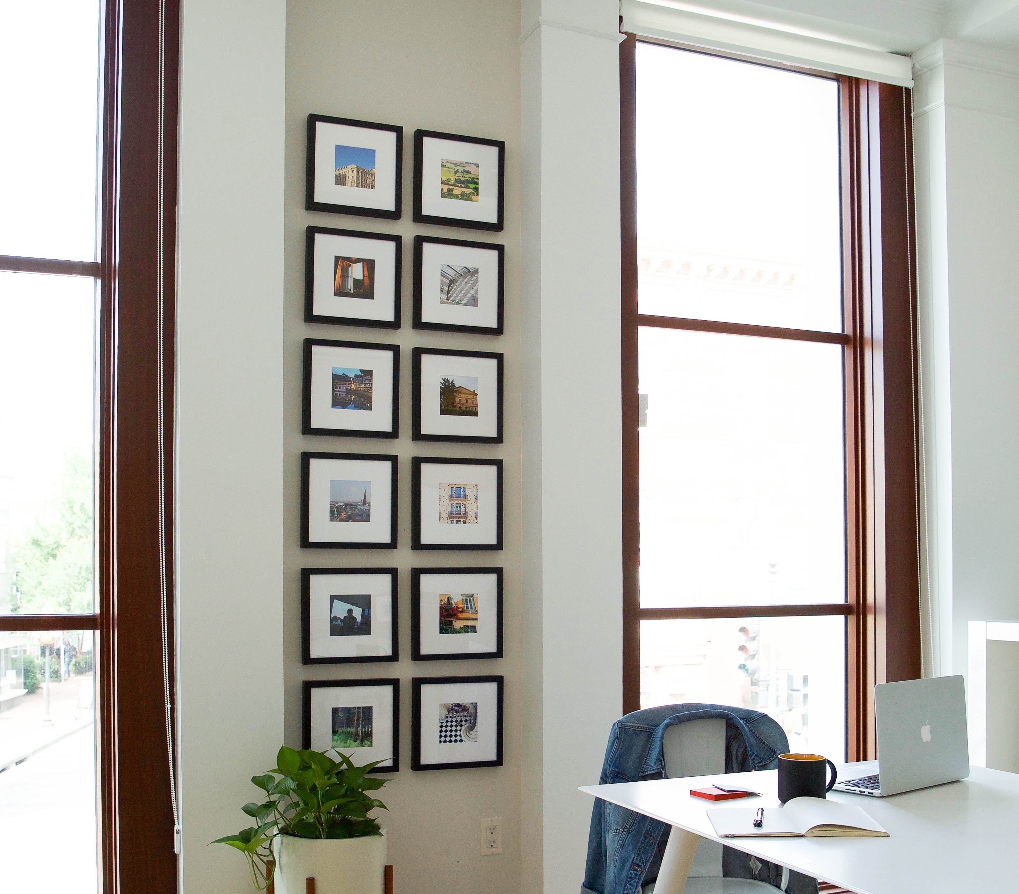 a gallery wall hung on a wall behind a desk with a laptop