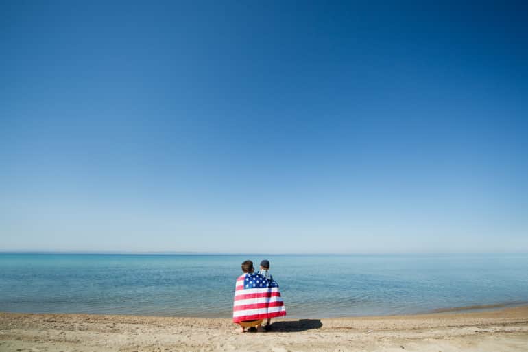 father and son looking at ocean from beach
