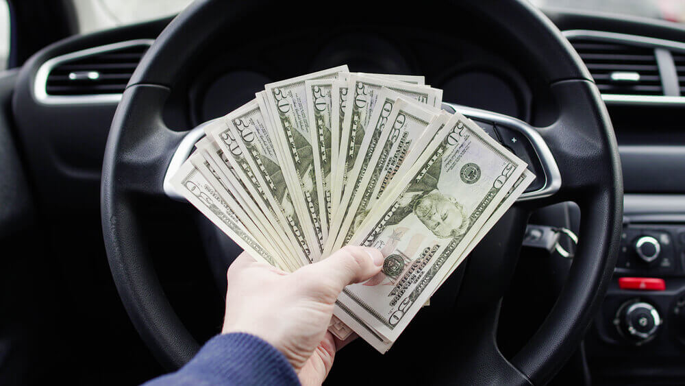 hand holding title loan cash in car
