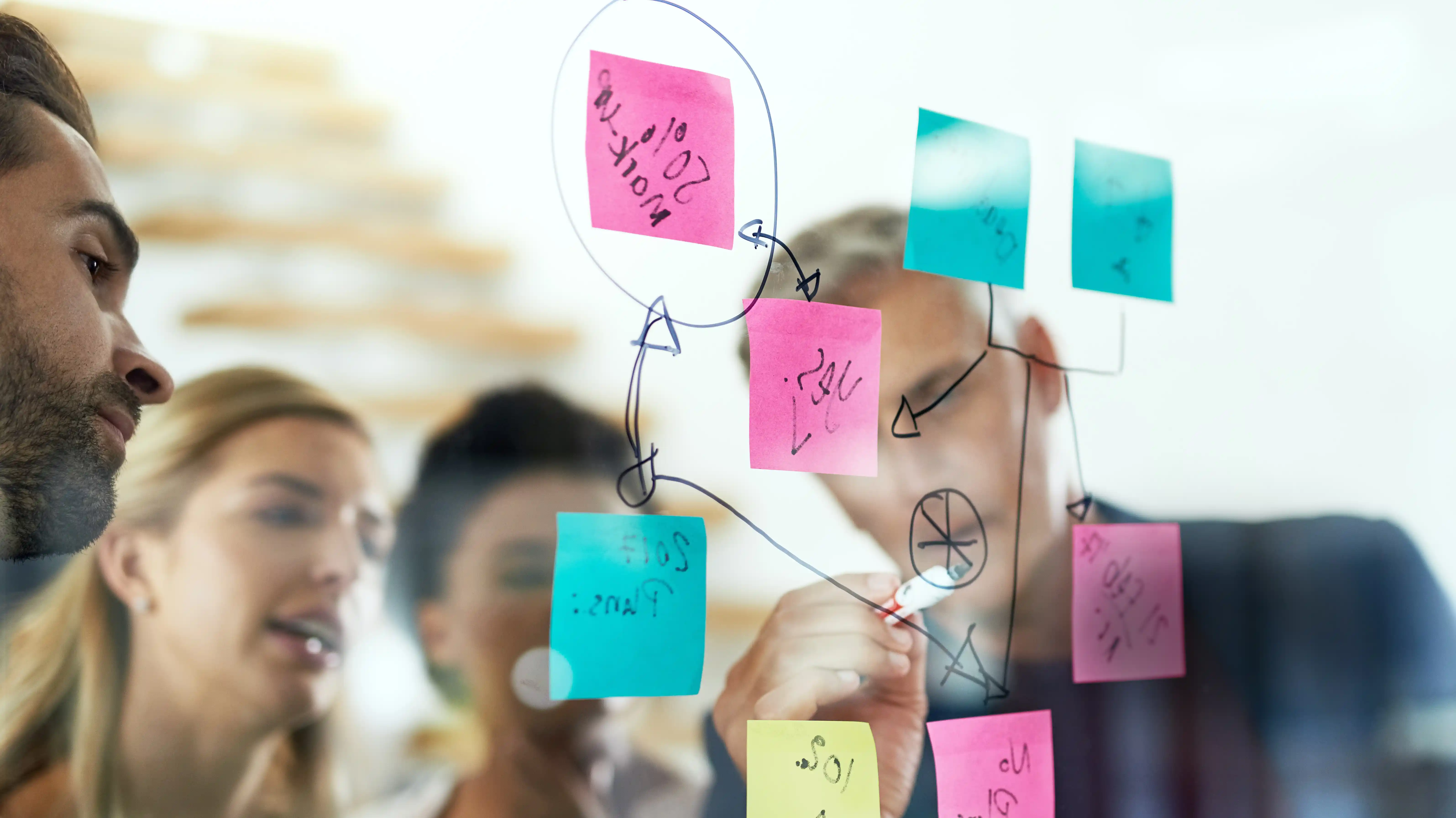 Diverse team brainstorming on glass board representing B Corp-driven innovation in marketing and sales