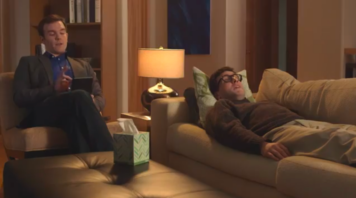 One man laying on sofa and oher man sitting in armchair