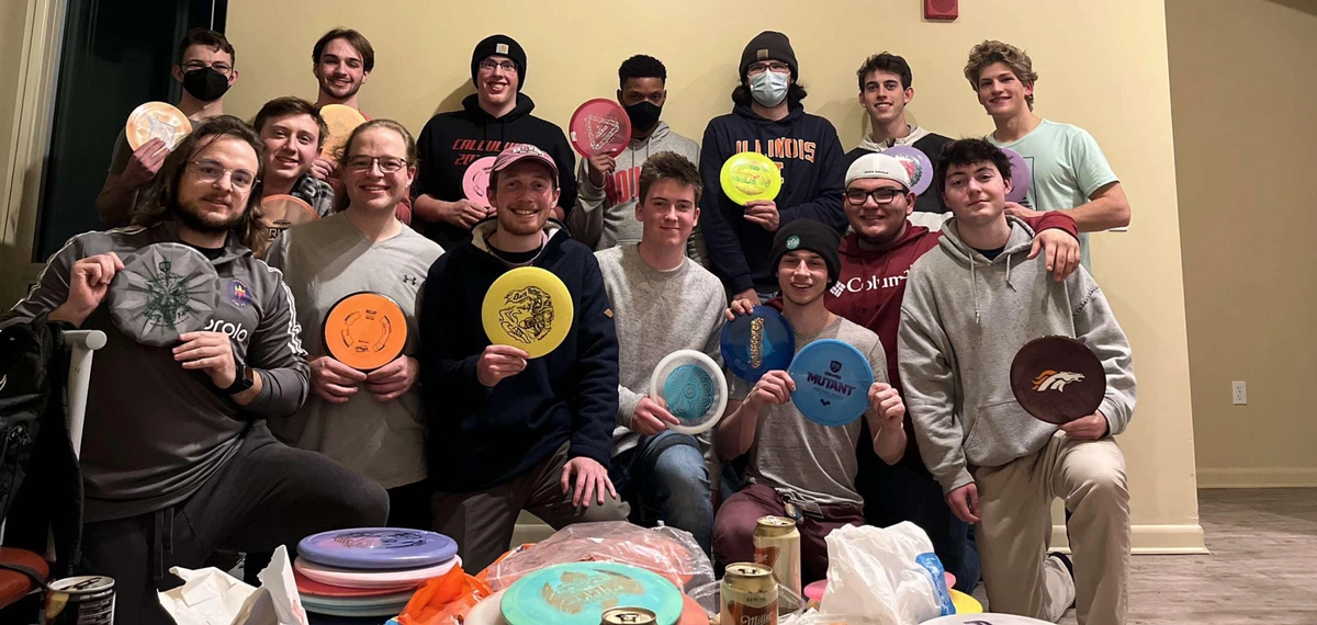 Indoor group photo with everyone holding up a disc for the camera