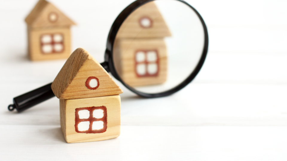Three miniature houses from woden bricks And magnifying glass