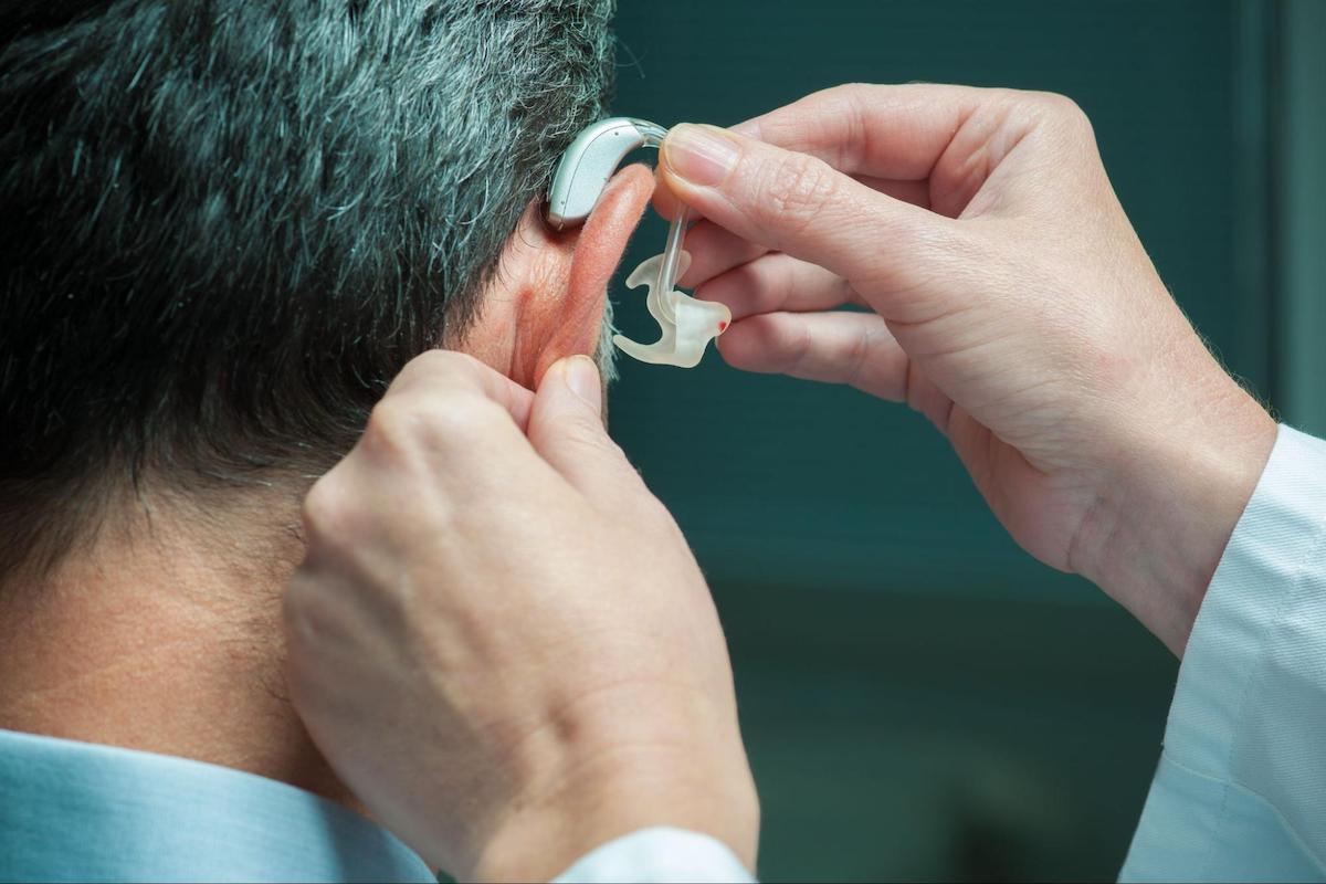 Doctor assisting a male patient in wearing a hearing aid