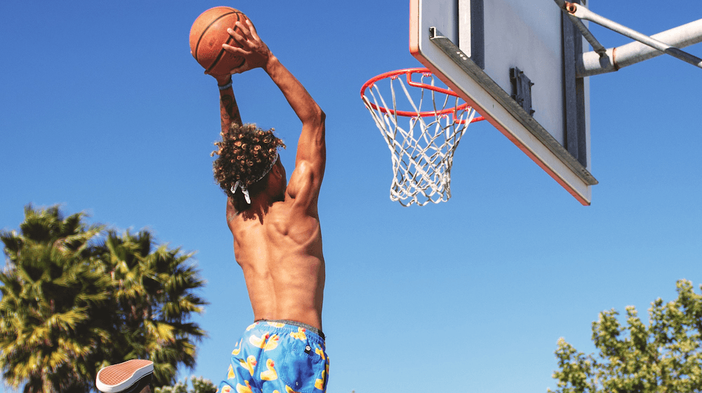 Young man slam dunking basketball