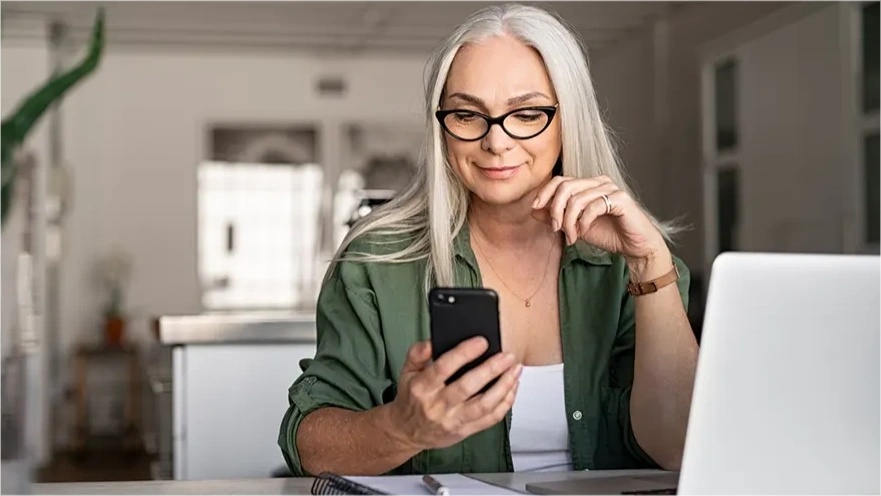 woman on laptop looking at phone