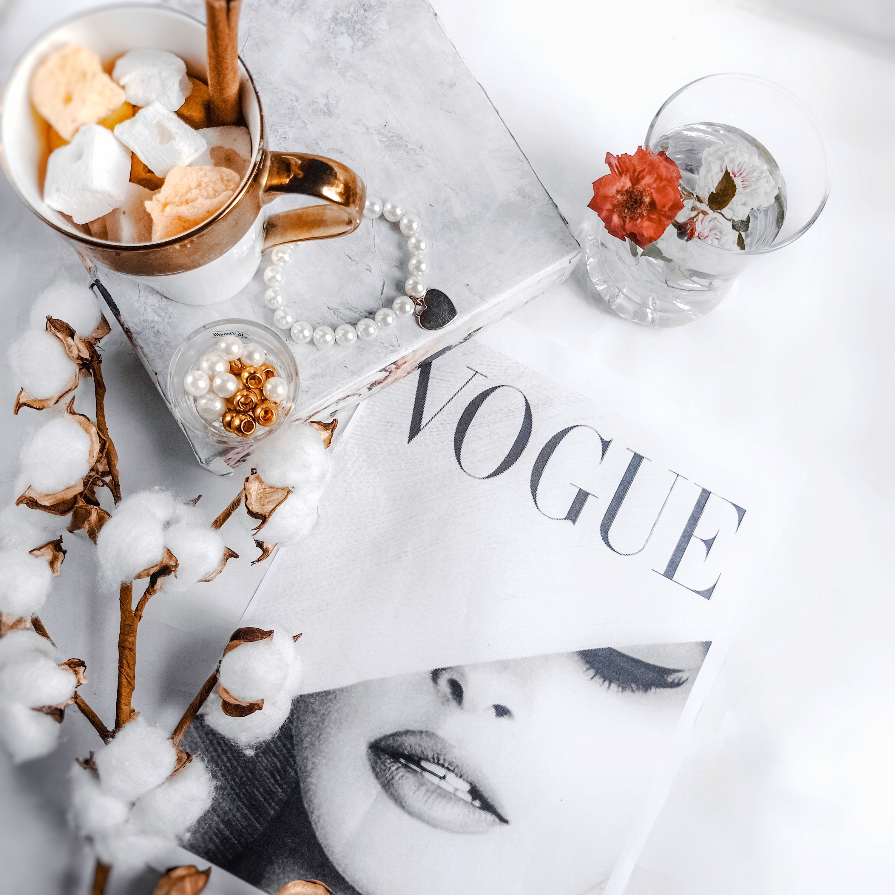 Vogue magazine on table with jewelry and cotton plant